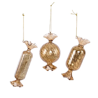 Three gold candy-shaped ornaments on a white background