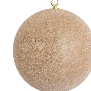 Gold glittery Christmas ball ornament on a light gray background