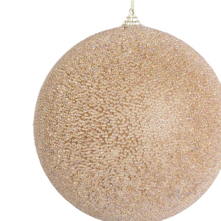 Gold glittery Christmas ball ornament on a light purple background