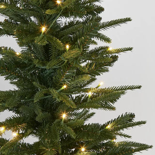 Close-up of a Christmas tree with lights against a gray background