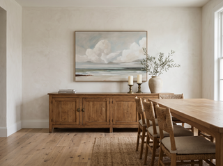 Hillston Ash coastal seascape canvas artwork displayed above a vintage timber sideboard in a refined dining room — olive branches in a ceramic vase, brass candle holders